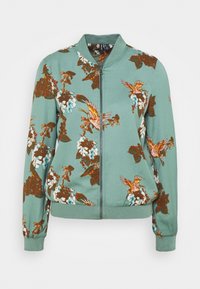 Chaqueta bomber verde claro con cierre frontal, que presenta patrones de flores y pájaros en marrón, rosa y azul. Cuello y puños de canalé.