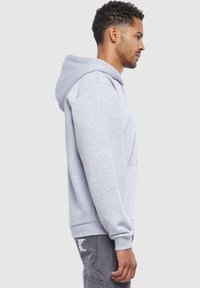 Gray hoodie made of cotton blend, featuring a kangaroo pocket and ribbed cuffs. The design includes a drawstring hood and relaxed fit.