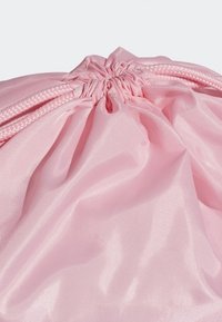 Dragkedja av snörning på en rosa satinpåsar med samlad tygt och flätade snören mot en ljus bakgrund.