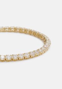 Pulseira de ouro com uma série de pedras de zircônia cúbica transparentes fixadas em cravação, apresentando uma textura lisa e polida.