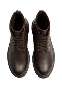 Brązowe skórzane botki za kostkę o teksturowanym wykończeniu, okrągłym nosku, brązowych sznurowadłach i czarnych gumowych podeszwach. Posiadają zamek błyskawiczny po boku do zapinania.