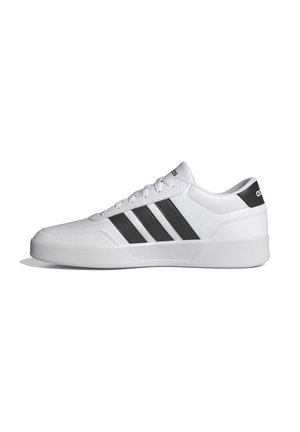 Biały niski sneaker z czarnymi trzema paskami Adidas i logo na pięcie oraz języku, pokazany z profilu.
