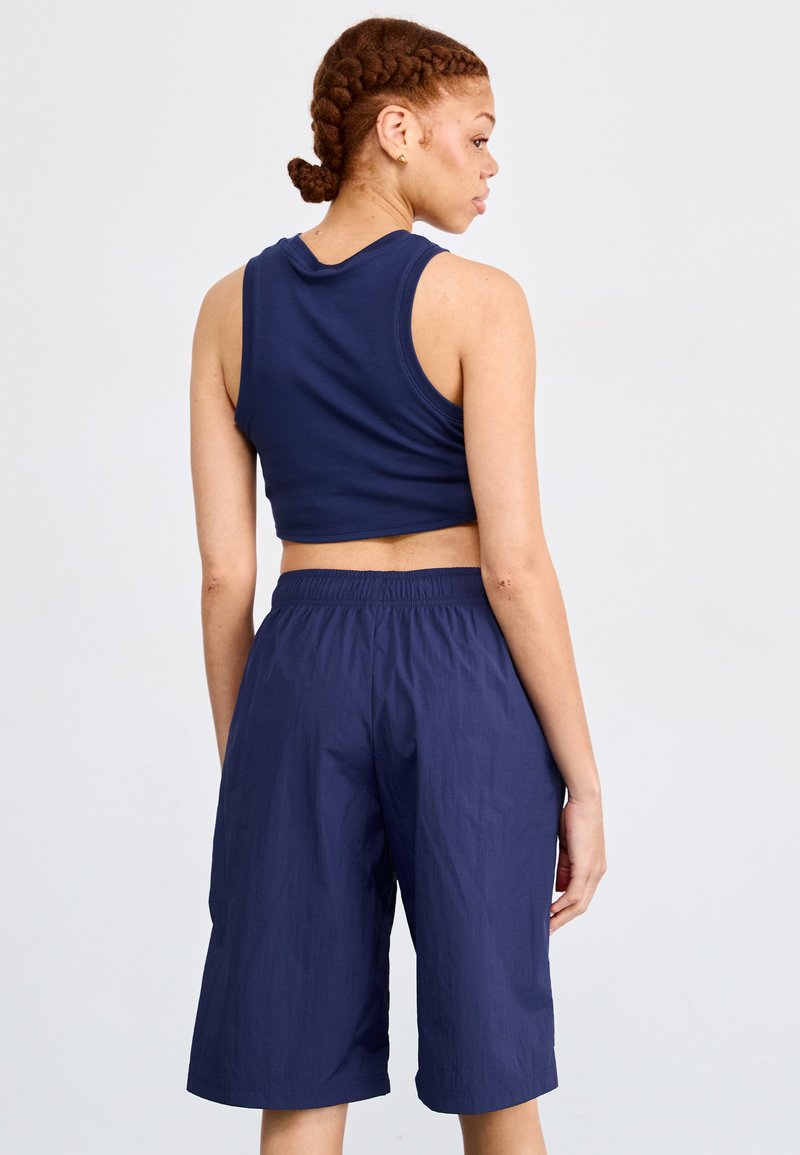Top sin mangas cortado color azul marino y pantalones cortos de talle alto a juego, hechos de una tela ligera; la textura parece suave y cuenta con una cinturilla elástica.