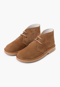 Stivali alla caviglia in suede marrone con punta arrotondata, design con lacci e suola in gomma marrone chiaro. Presenta cuciture lungo il bordo della suola e asole.