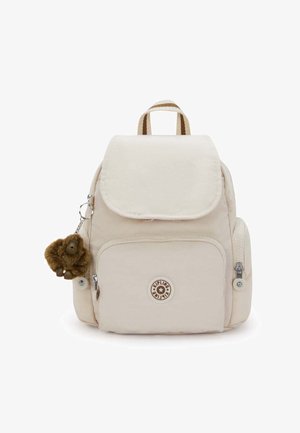 Mały beżowy plecak z przednią kieszenią, bocznymi kieszeniami na zamek, paskiem w paski i brązowym pluszowym breloczkiem w kształcie małpki.