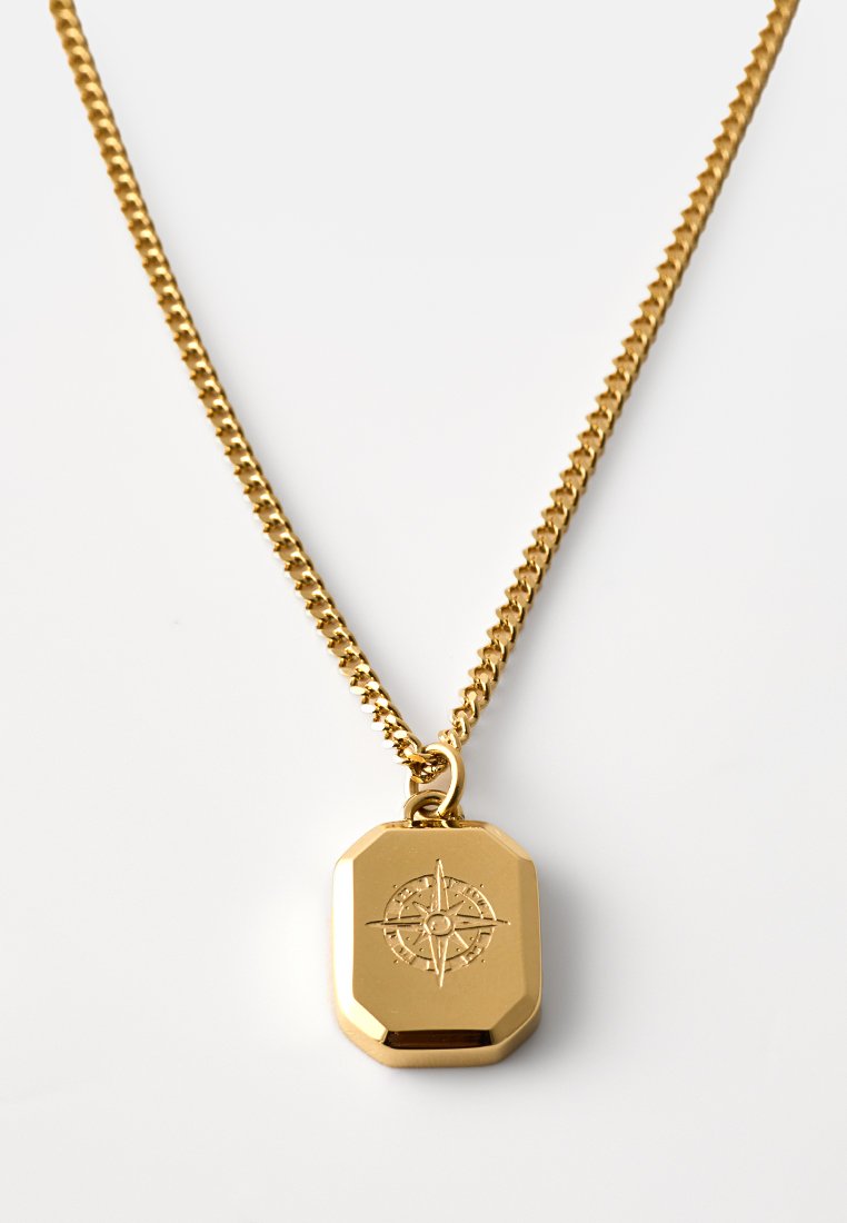 Goldener Anhänger mit einem strukturierten Kompassdesign, an einer strukturierten goldenen Kette, mit einer oktagonalen Form und glatter Oberfläche.