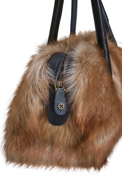 Sac à main en fourrure marron avec des poignées en cuir noir et une fermeture éclair noire avec un tirette dorée présentant un petit motif floral.