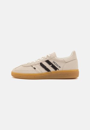 Baskets Adidas Spezial beige avec des bandes noires et une semelle en caoutchouc naturel, vues de côté sur fond blanc.