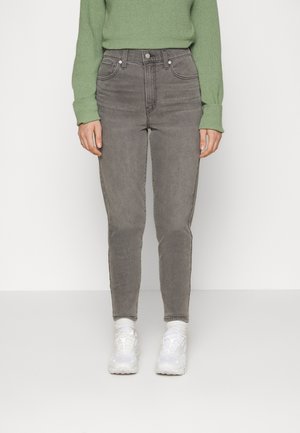 Gray high-waisted jeans with a slim fit, featuring five pockets, subtle fading, and a belt loop, worn with white sneakers and a green sweater.