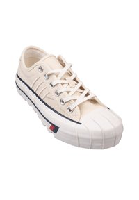 Baskets en toile de couleur écru avec un embout en caoutchouc, des lacets blancs et des œillets en métal argenté. Comprend une rayure bleu marine et une petite touche de rouge, blanc et bleu.