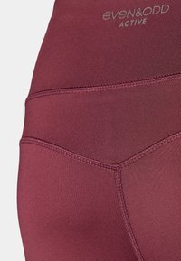 Μπορντό ενεργά κολάν με λεία υφή, ραμμένες λεπτομέρειες και ψηλή μέση με λογότυπο. Ραμμένο σχέδιο με κολακευτικό σχήμα.