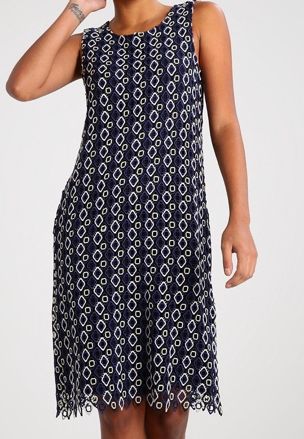 Robe sans manches bleu marine avec motif géométrique blanc, ourlet festonné et tissu léger texturé, offrant une coupe décontractée pour plus de confort.