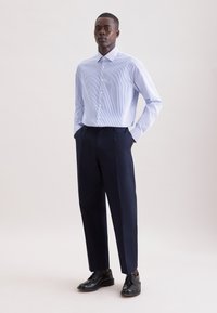 Camicia a righe azzurro chiaro e bianco, maniche lunghe, collo abbottonato, abbinata a pantaloni blu navy su misura e scarpe eleganti nere.