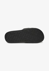 Zwarte rubberen sandaalzool met een patroon voor grip en een verhoogd merkteken. Getextureerd voor grip met een afgeronde teen en een open hielontwerp.