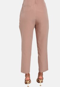 Lys rosa, lige bukser med sidelommer, glat tekstur og skræddersyet pasform. Sammen med beige højhælede sandaler.