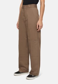 Bruine wijde broek met hoge taille, voorplooien en zijzakken. Bevat een logo-opdruk op de dij en een gestructureerde stof.