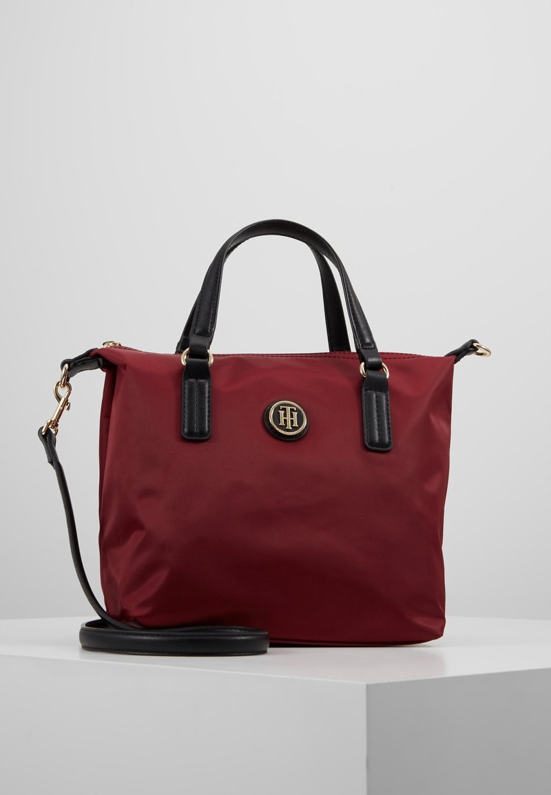 Borsa a mano in nylon rosso con accenti in pelle nera, manici superiori e tracolla removibile. Presenta una placca con logo dorato sulla parte anteriore.