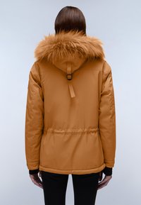 Gul-orange polstret jakke med hætte i kunstpels, justerbar rem og indsnævret talje. Glat tekstur, praktisk design.