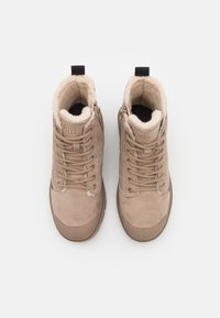 Bottes beige à la cheville avec doublure en fausse fourrure, dotées d'une tige en cuir texturé, fermeture à lacets à l'avant, fermeture éclair latérale et bout arrondi.