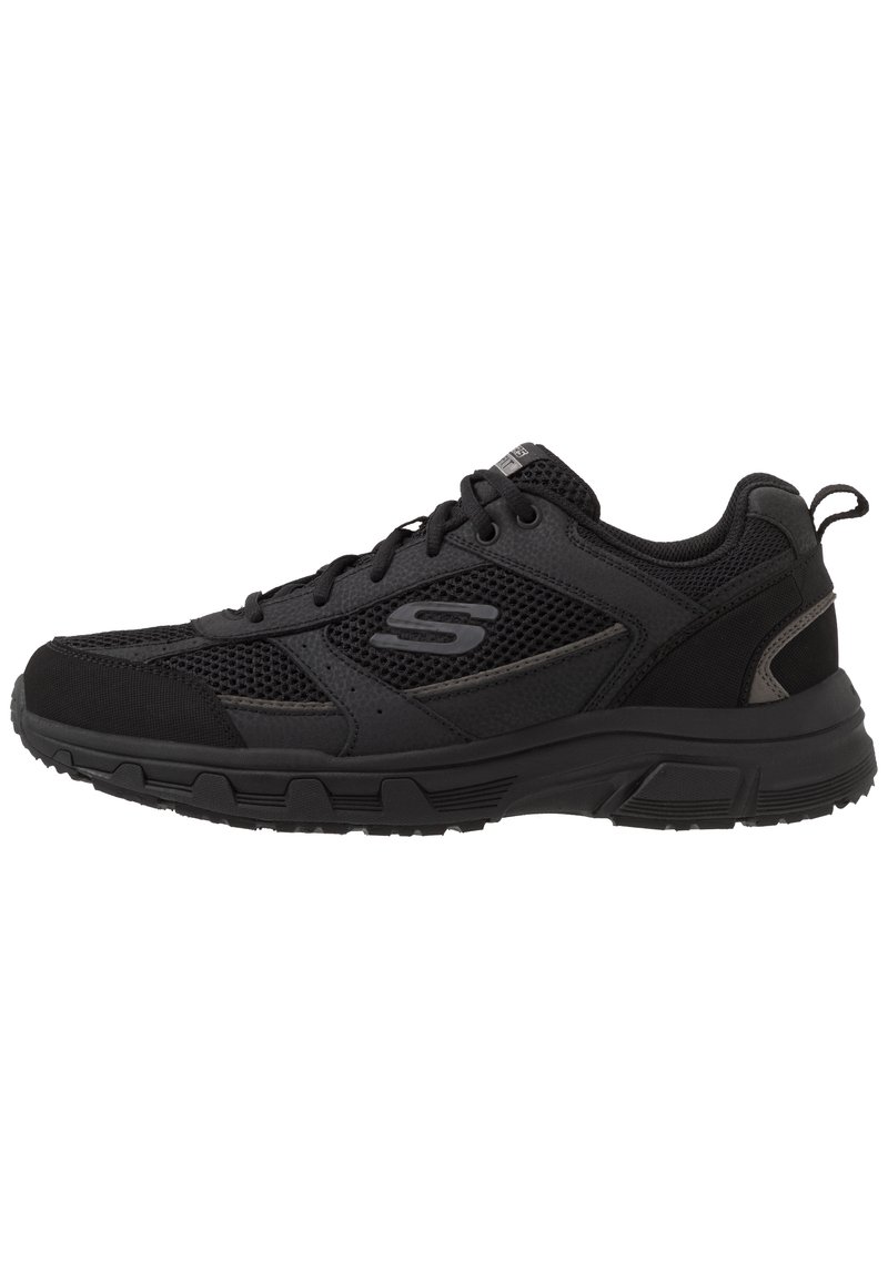 Zapatilla deportiva negra con parte superior de malla y sintética, diseño de cordones, cuello acolchado y suela de goma texturizada con un prominente patrón de agarre.