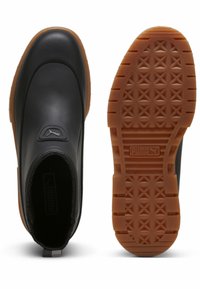 Zwarte waterdichte enkellaarzen met een gladde bovenkant, elastische zijpanelen en een gestructureerde bruine rubberen zool met een diamantpatroon.