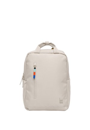 Zaino beige chiaro a forma quadrata con maniglie superiori, tasca frontale verticale con cerniera e tirazip colorato, e logo "GOT BAG." in basso a destra.