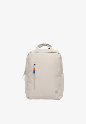 Lysebeige rygsæk i firkantet form med øverste håndtag, en lodret lynlåslomme foran med farverig trækfane og logoet "GOT BAG." nederst til højre.