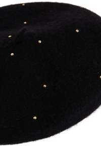 Béret de fieltro negro adornado con remaches de color dorado, con una forma redondeada y una textura suave. Un sutil detalle de costura realza el diseño.