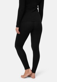 Schwarze Leggings aus weichem Material mit schlanker Silhouette und glatter Textur, entworfen für eine enge Passform von der Taille bis zum Knöchel.
