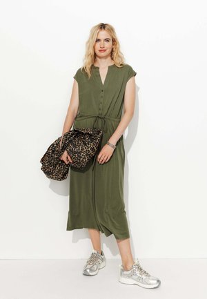 Robe vert olive avec des manches courtes, bouton avant et taille à cordon ; associée à des baskets argentées et un sac à imprimé léopard.