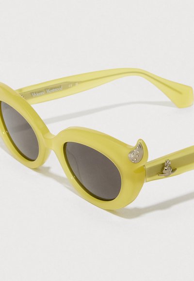 Κίτρινα oversized γυαλιά ηλίου με σκούρους φακούς, γυαλιστερό σκελετό και διακοσμητικές ασημένιες λεπτομέρειες στους βραχίονες. Μοναδικό στρογγυλό σχήμα.