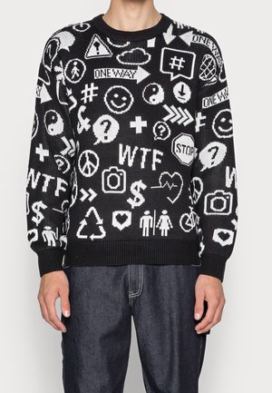 Pull noir avec des motifs graphiques blancs, comprenant des symboles et des émojis. Présente un col et des poignets côtelés, avec une coupe décontractée.