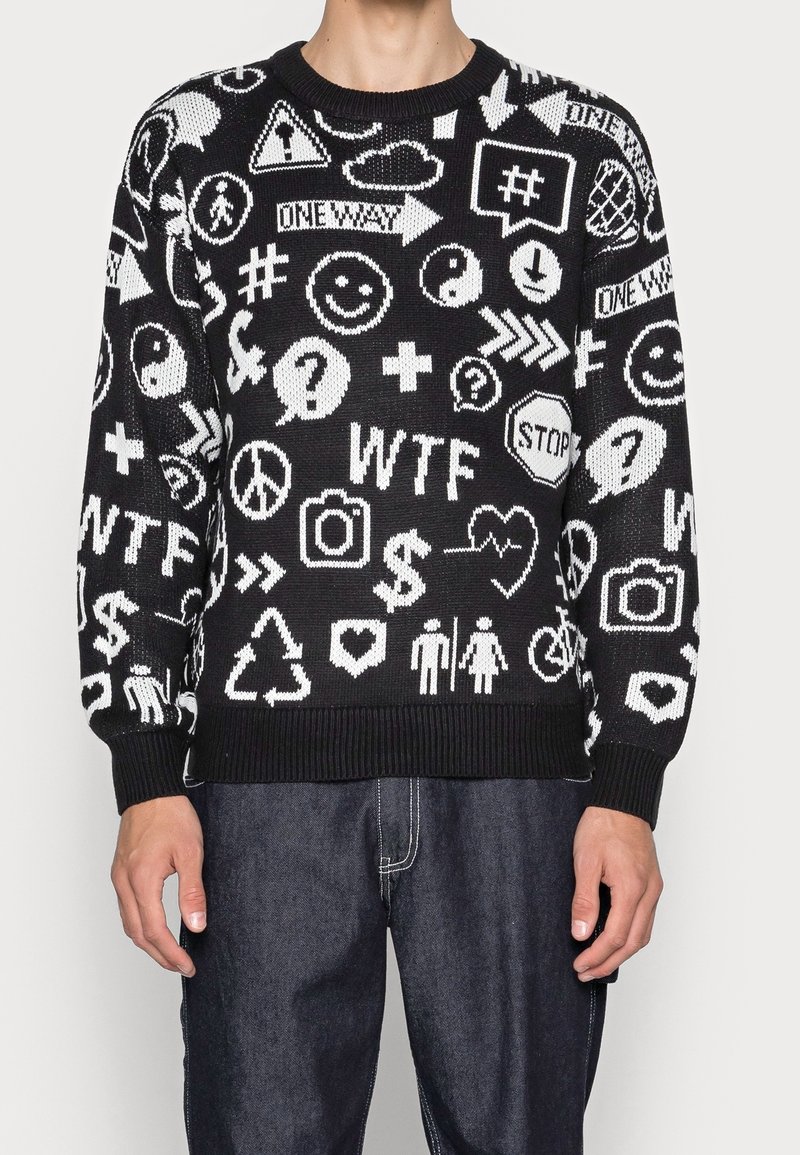 Maglione nero con motivi grafici bianchi, inclusi simboli ed emoji. Presenta un colletto e polsini a costine, con una vestibilità rilassata.