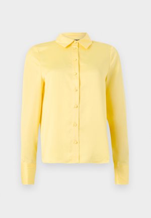 Blouse jaune à manches longues avec col, fermeture à boutons sur le devant et texture lisse. Design simple sans motifs ni accents.