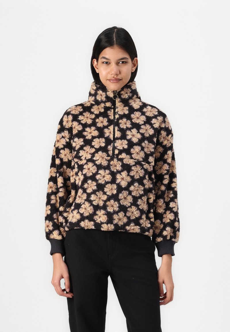 Sudadera de forro polar con cuello alto, con un fondo negro y patrones florales en color beige. Cierre con cremallera en la parte delantera y puños acanalados.