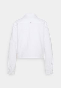 Cropped white shirt with long sleeves, button cuffs, classic collar, and a single back pleat detail. Made from smooth cotton fabric.