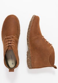 Hnědé kožené kotníkové boty s kulatou špičkou, prošívanými detaily, svázáním na tkaničky a strukturální gumovou podrážkou. Hladký povrch s matným finišem.