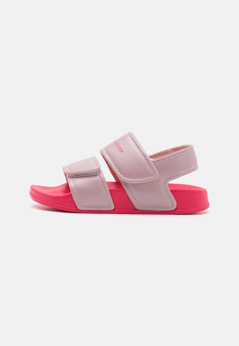 Pink and light purple sandals with two Velcro straps, textured sole, and a flat design. Notable logo on the strap in red.