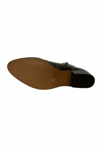 Zapato de cuero negro texturizado con un tacón bajo y una suela exterior lisa de color marrón claro. Presenta una decoración en la parte superior y detalles de costura en los lados.