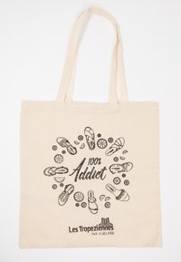 Borsa tote in tela beige, con stampa nera di vari sandali e il testo "100% Addict" con accenti attorno.
