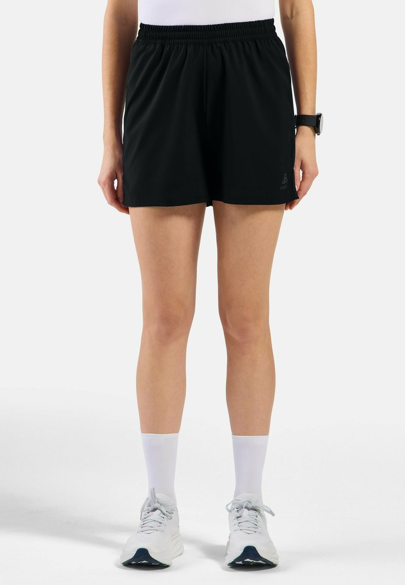 Zwarte sportshorts met een elastische tailleband, rechte snit en logodetail op de onderste zoom, in combinatie met witte sokken en sneaker.