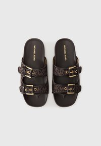 Chanclas marrones con dos correas ajustables con hebillas y un estampado del logo de MK, suela plana y acentos de hardware en tono dorado.
