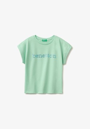 Jasnozielony t-shirt z krótkim rękawem i okrągłym dekoltem, z niebieskim kropkowanym napisem "benetton" nadrukowanym na piersi.