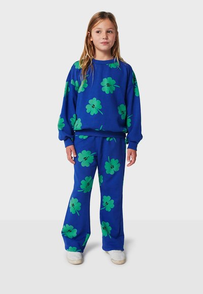 Ensemble sweat-shirt et pantalon bleu avec de grands motifs floraux verts. Le tissu semble doux avec une coupe décontractée et des manches longues.