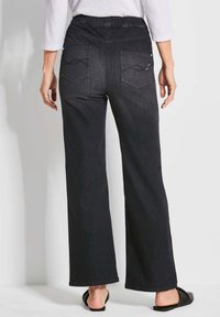 Un pantalon en denim foncé à jambes larges avec une taille élastique, deux poches arrière avec des coutures incurvées et un design classique à cinq poches.