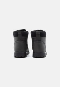 Crne vodootporne gležnjače s teksturiranom kožnom vanjštinom, mekanim postavom od flisa na ovratniku i čvrstim gumiranim potplatima za dobar grip.