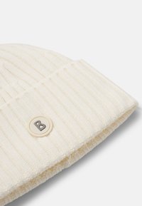 Kremowa, prążkowana dziana czapka z mankietem i okrągłą naszywką z logo „B.” Miękka w dotyku, uniwersalny design, idealna na zimne dni.