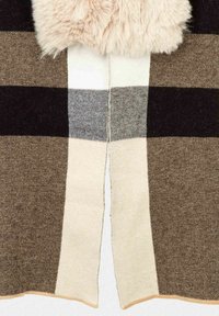 Manta de cuadros tejida en tonos de marrón, negro y crema. Presenta un borde de pelo beige en la parte superior y bordes sin rematar a lo largo de los lados.