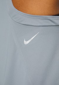 Personne portant un t-shirt de sport bleu clair avec un logo Nike swoosh blanc près de l'encolure sur la poitrine.