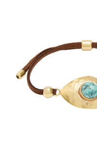 Bransoletka w kolorze złotym z metalowymi elementami, z turkusowym kamieniem umieszczonym w młotkowanej owalnej oprawie, na brązowym suknie z złotymi akcentami.